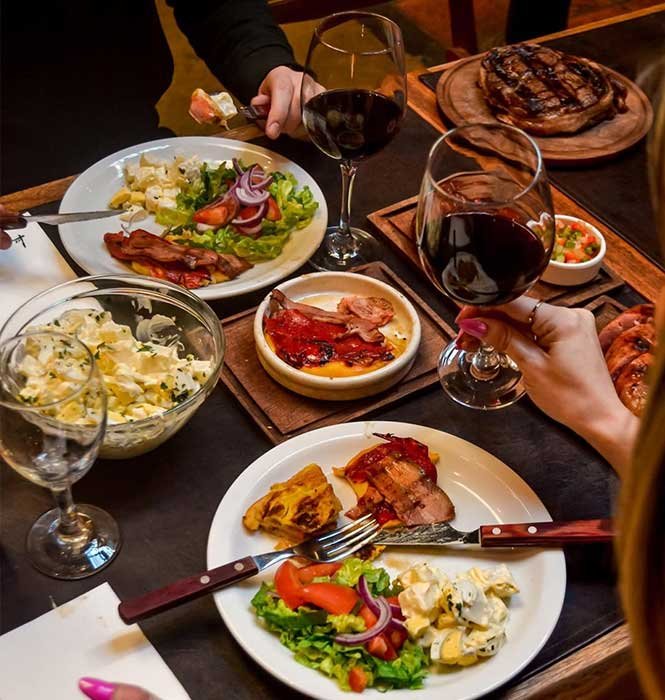 Mesa con variedad de platos y copas de vino para un grupo